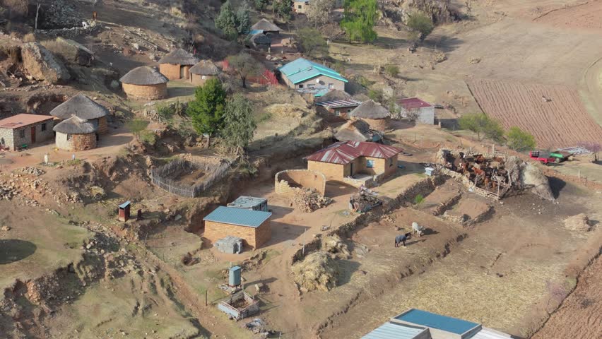 Aerial view of general activity in Basotho rural village. Houses and livestock at foot of hill