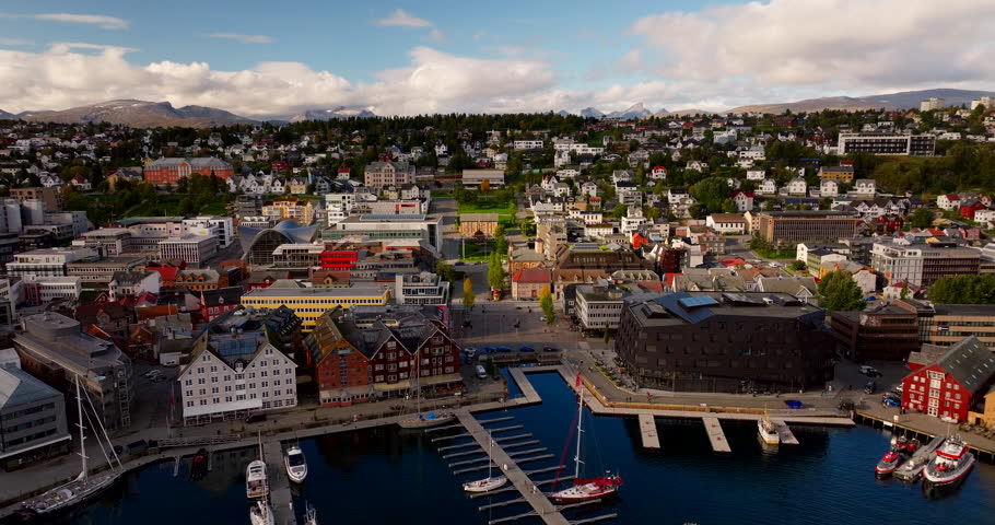 Tromsø waterfront and marina in early autumn, northern Norway. City skyline, harbor boats and colorful buildings under soft daylight, picturesque travel destination, aerial view