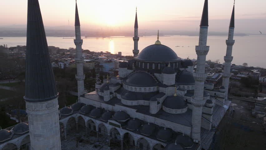 Aerial drone footage of the Blue Mosque (Sultan Ahmed Mosque) in Istanbul, Turkey. The iconic Ottoman mosque features a large central dome surrounded by cascading semi-domes and six slender minarets, standing prominently within the historic Sultanahmet district. This monumental religious landmark represents one of Istanbul’s most recognizable symbols, ideal for travel, documentary, culture, religion, and architectural visual projects.