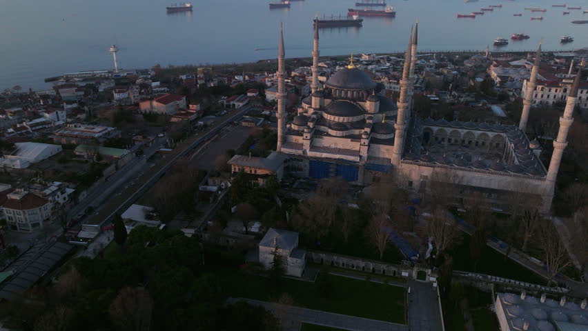 Aerial drone footage of the Blue Mosque (Sultan Ahmed Mosque) in Istanbul, Turkey. The iconic Ottoman mosque features a large central dome surrounded by cascading semi-domes and six slender minarets, standing prominently within the historic Sultanahmet district. This monumental religious landmark represents one of Istanbul’s most recognizable symbols, ideal for travel, documentary, culture, religion, and architectural visual projects.
