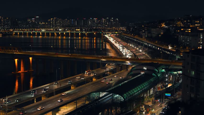 High angle aerial view of busy nighttime vehicle traffic on the Gangbyeonbuk-ro expressway passing Oksu Station and the Han River riverside in Seoul South Korea