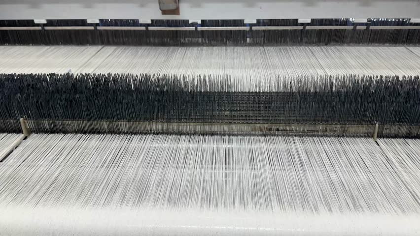 Textile fabric being woven on industrial loom machine, close-up view
