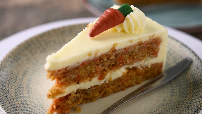 Carrot cake slice with cream cheese frosting on wooden table