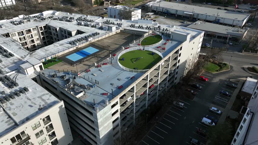 Aerial view of modern rooftop parking garage in Nashville, USA, with landscaped green spaces, recreational areas and surrounding urban residential buildings. Approaching shot. Tennessee state.