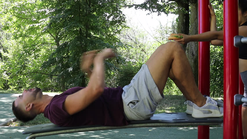 Man eating a hamburger while doing some abs 