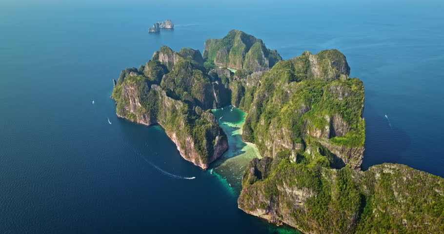 Aerial panorama of Phi Phi Leh island limestone karsts rise from the emerald ocean, forming Maya Bay with its clear turquoise lagoon and boats enjoying the tropical paradise. Travel, holiday, relax