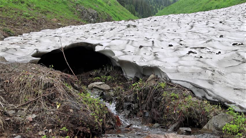 Close-up melting glacial stream flowing over rocks in mountains.