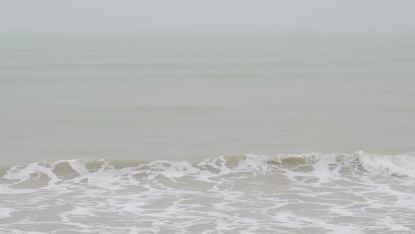 landscape view of heavy wave oceanic foam is coming to the beach while in storming heavy raining weather. aerial footage landscape and water waves with nobody. vacation outdoor landscape texture