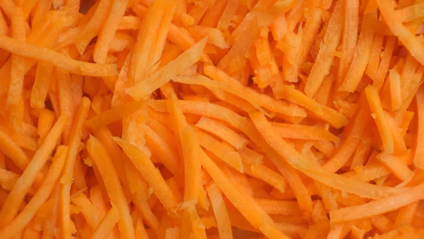 Vibrant texture of shredded raw carrots rotating, macro top view