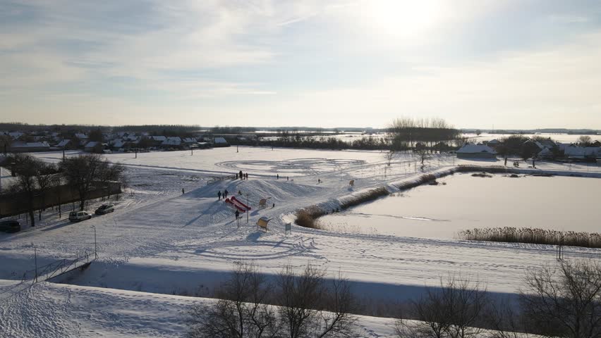 Children and families enjoying winter activities, playing and sledding on snowy hills in Kiskunmajsa, Hungary