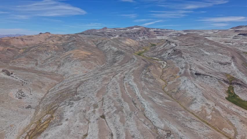 Aerial reverse shot reveals red, yellow, and green lava trails covered in salt, showing Peru’s unique mineral volcanic terrain.