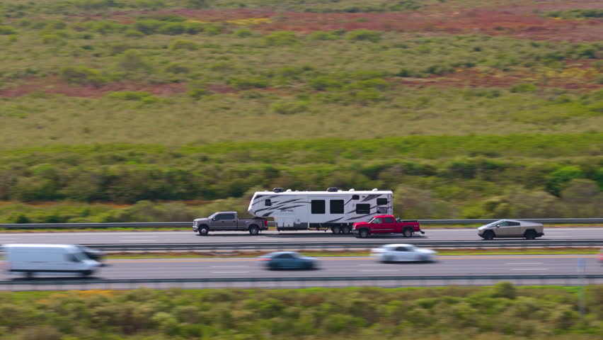 Pick-up truck towing camper trailer driving at high speed on American freeway. RV travel in USA.