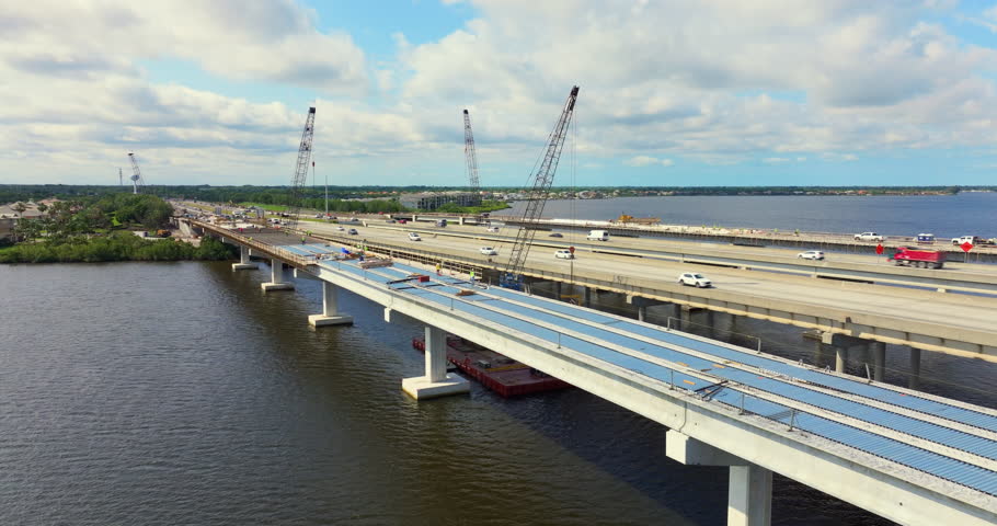 Highway bridge construction in Ellenton, Florida. Development of Trooper J.D. Young Memorial Bridge crossing the Manatee River. American freeway road with moving traffic cars.