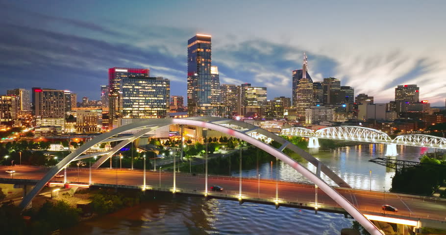 Downtown district highway bridge traffic in Nashville city, Tennessee at night. Brightly illuminated high skyscraper buildings in modern American midtown.
