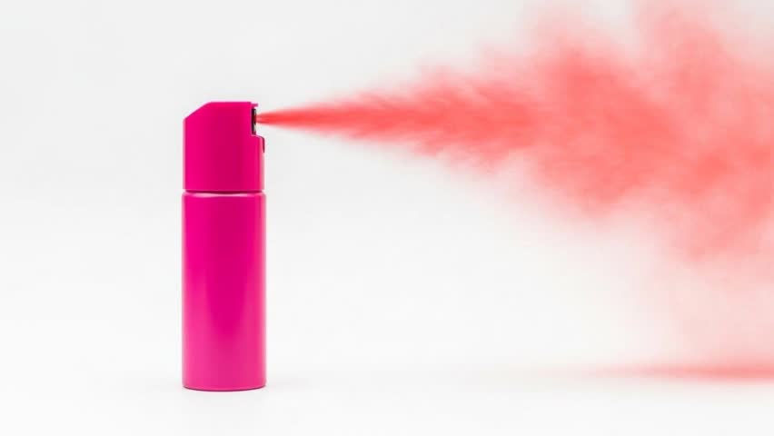 A close-up video of a bright pink spray can ejecting a cloud of coral-colored mist. The clean white background emphasizes the action and vibrant color, suitable for product or abstract concepts.