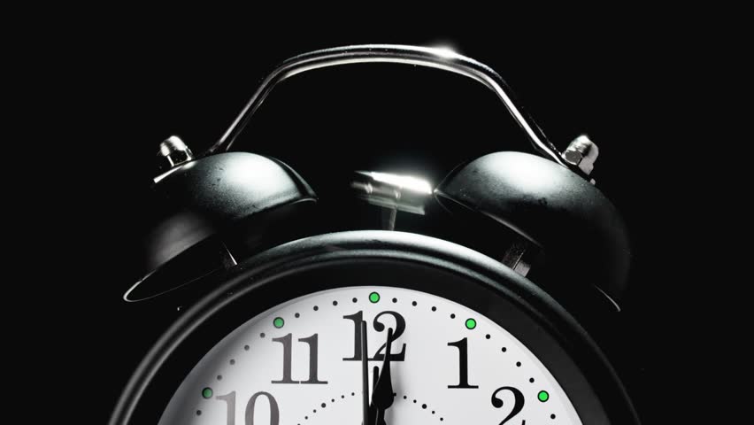 Black and white vintage alarm clock on black background. Old fashioned alarm clock with bells. Time moving fast. Time concept. Wake up to work. 4K, UHD