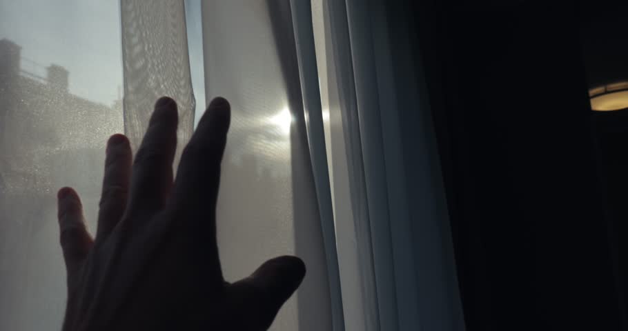 Window curtain with sunlight outside, tired human hand moving, opening curtain, looking at the sun and street