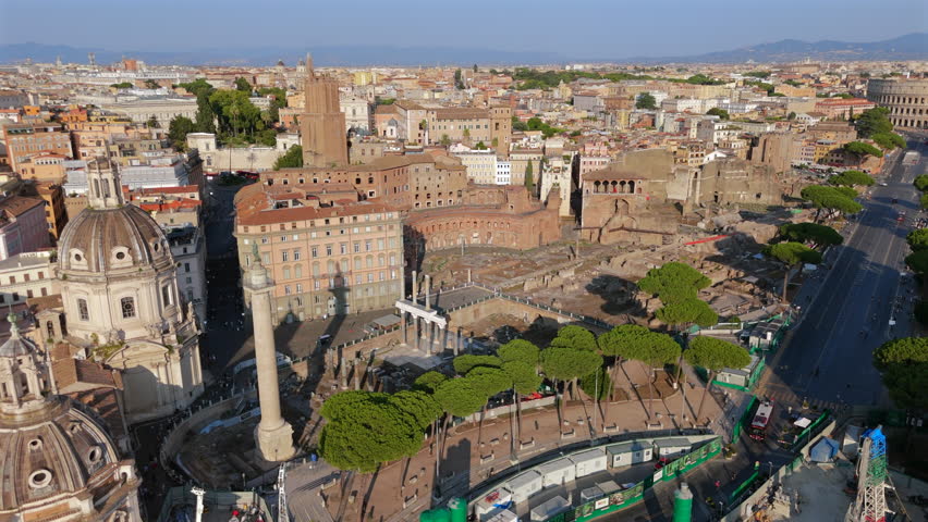 Drone aerial panorama of Roman Forum ruins and surrounding historic buildings showing layered history, stone columns, city blocks and urban texture of Rome Italy. clear daylight viewsky