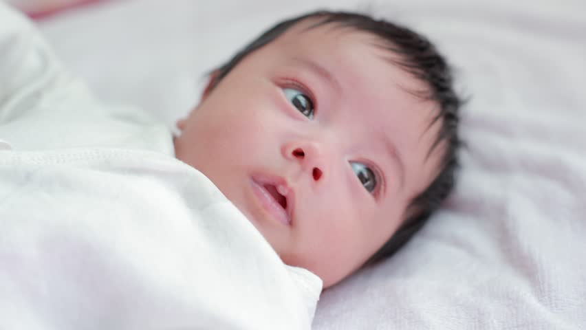 The baby sleeps on a white bed.