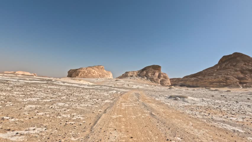 Cinematic offroad driving through white desert valley with rocky hills and sandy surface