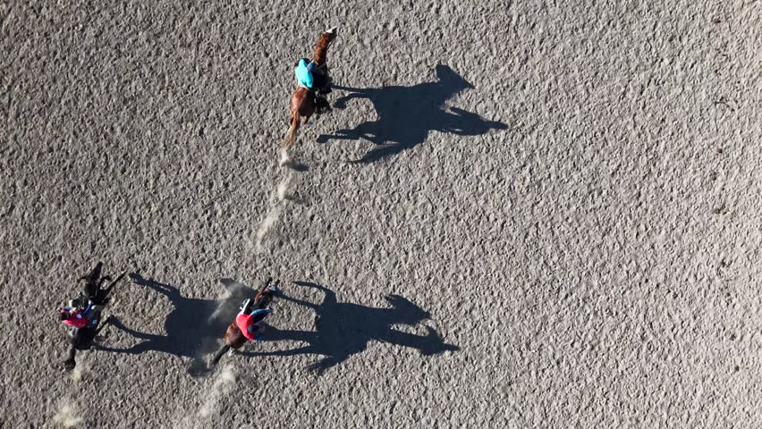 Top-down aerial footage of nomadic riders playing the traditional horse game Kok Boru in Kyrgyzstan, featuring harsh midday shadows on a dusty arena.
