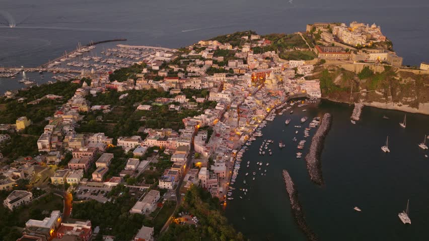 Aerial View Of Procida Island With Corricella Port, Terra Murata Hill, And Procida Marina At Dusk In Italy.