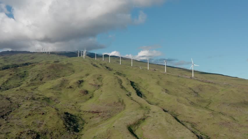 daytime green hills with wind turbines under partly cloudy blue sky and scattered white clouds over Maui Hawaii
