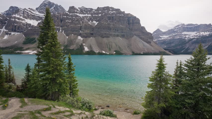 The stunning, glacier-fed turquoise Bow Lake in Alberta, Canada, located directly off the Icefields Parkway in Banff National Park with waves gently lapping against shore as a small breeze blows