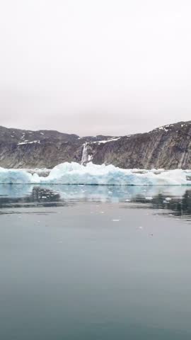 Arctic landscape with icebergs and waterfall in Greenland