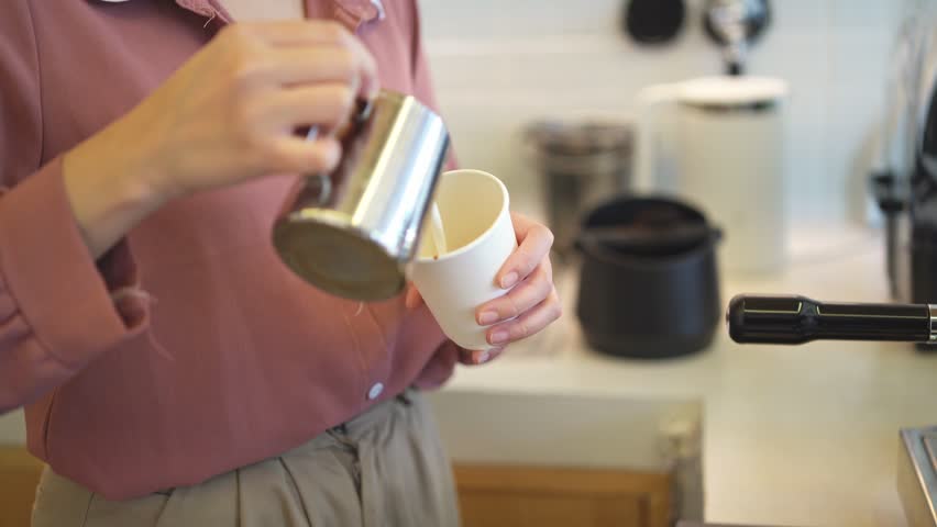 Woman in Pink Blouse Preparing Coffee in Home Kitchen with Modern Appliances and White Cups for a Relaxing Morning Routine Experience