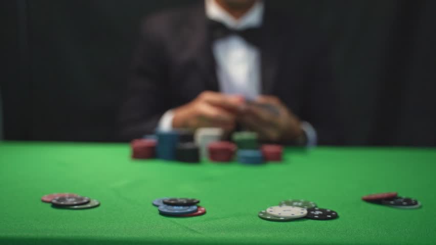Professional Card Player at a Casino Table Counting Chips with Focused Expression on a Green Felt Surface for Gambling Photography