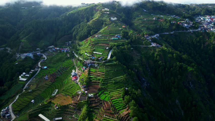 Slow side left aerial over Atok Benguet, Halsema Highway former highest mountain area in the Philippines showing a zigzag highway leading into lush vegetable fields a rural mountain farming.