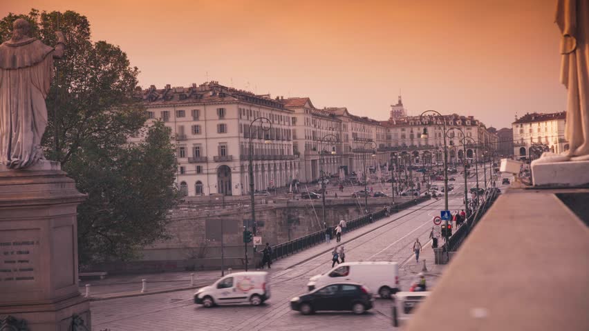Turin, Italy, timelapse. Cityscape view of historic architecture, bridge traffic, and pedestrians at sunset. Fast motion video of Piazza Vittorio Veneto area during dusk.