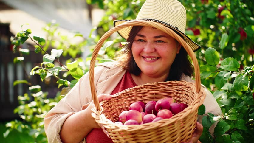A Joyful Woman Holding a Basket of Freshly Picked Apples in a Lush Orchard, Embracing Nature