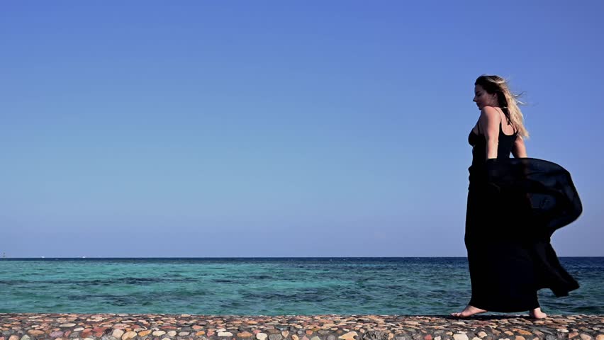 Dancer Moves Gracefully Along the Beach in Slow Motion With Wind Blowing on a Sunny Day at the Ocean in Africa