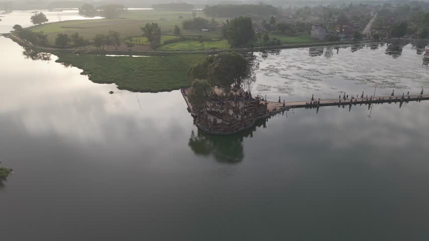 Aerial view of a lake with a structure, a bridge, and shoreline