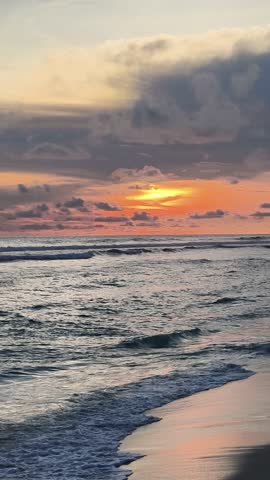 A calm sunset over the ocean, where gentle waves meet the shore under a soft, glowing sky.