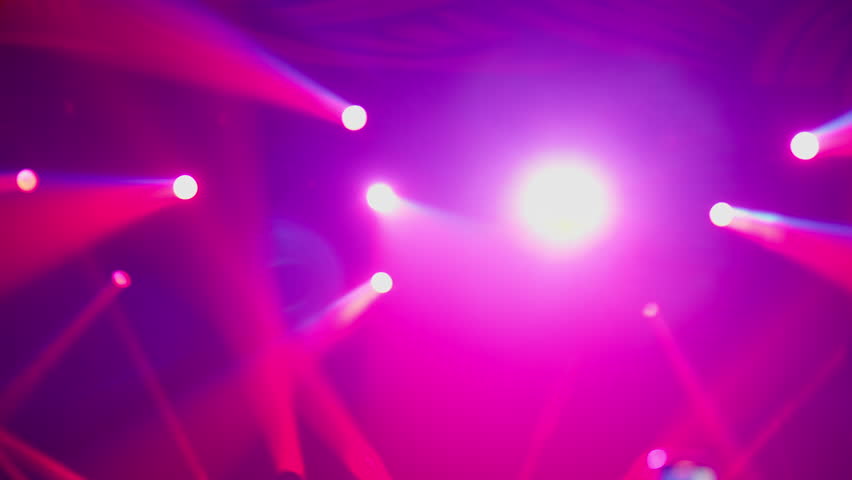 Flashing and moving stage lights in a concert venue or nightclub. Colorful beams of light-blue, red, orange, and purple-scan through a hazy atmosphere. Energetic lighting effects for a live event.