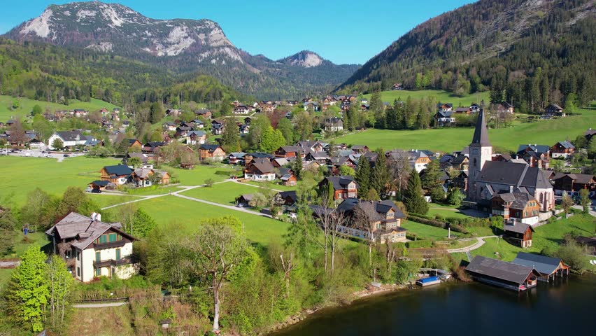 Aerial view of Altausseer See and village surrounded by mountains reflecting in calm alpine waters. Austria, Salzkammergut. Nature beauty in summer season