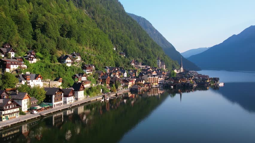 Explore the aerial perspective of UNESCO Hallstatt historical village in Salzkammergut, Austria with picturesque lakeside homes, calm lake, and Alp mountains. A tranquil scene reflecting nature beauty