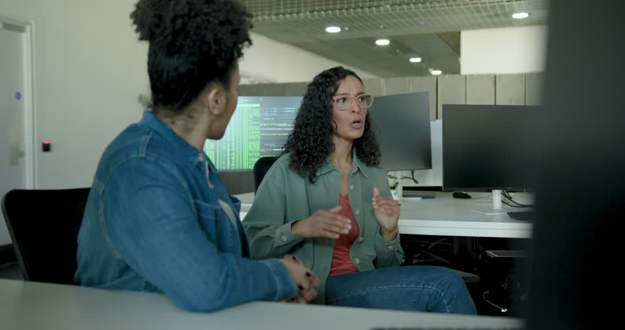Two Women collaborating on tech solutions in an office using Desktop Computer