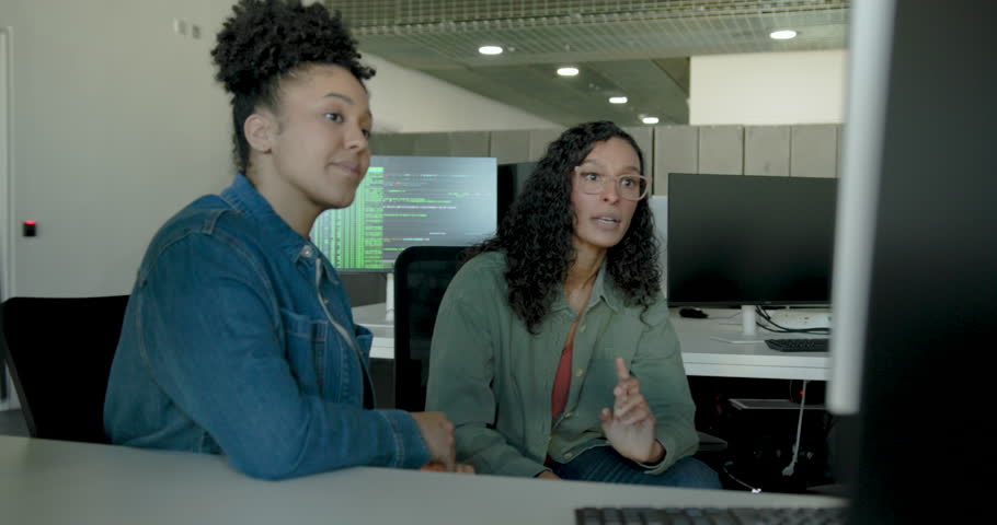 Two Women collaborating on tech solutions in an office using Desktop Computer