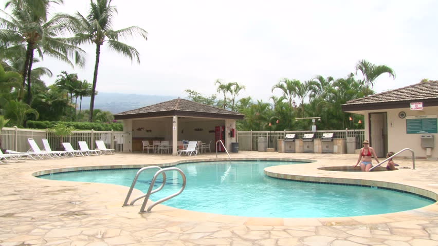 Man dives into swimming pool at tropical island resort in Hawaii.