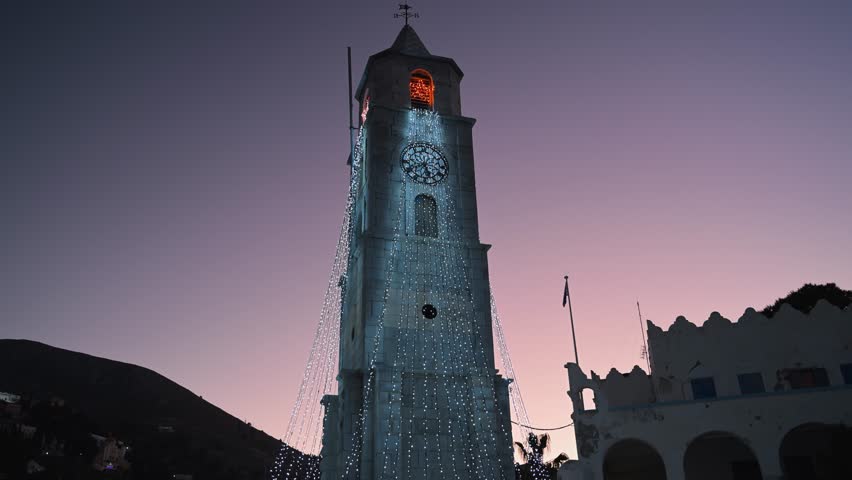 Evening view of a tower illuminated with Christmas lights in Symi, Greece during dusk transitioning into night