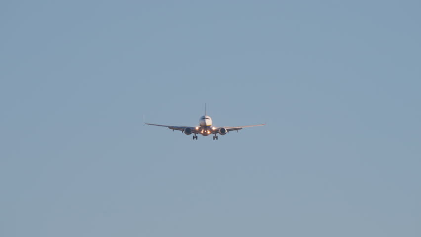 Dramatic video of a commercial passenger jet on final approach. The airplane flies closer, culminating in a powerful low-angle shot as it passes overhead against a clear blue sky.