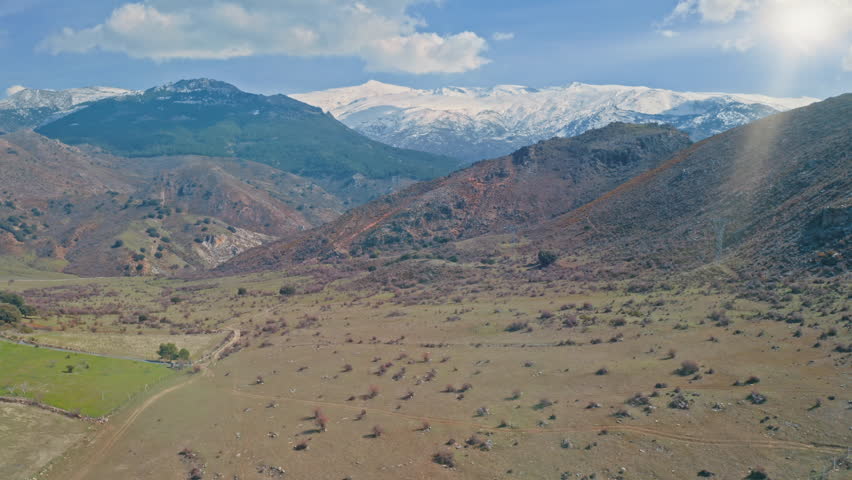 Aerial view of Sierra Nevada mountains in autumn weather season dry land Granada snowy peaks and blue sky shining sunlight sunny landscape panorama of Andalusia from above Spain traveling in Europe