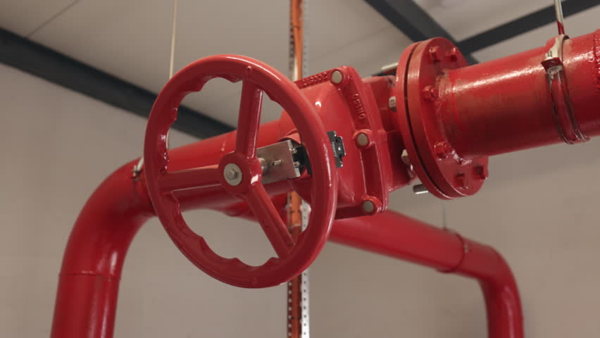 fire protection, red piping, Red valve. Close-up red metal valve on overhead industrial pipeline, likely part fire suppression or sprinkler system.
