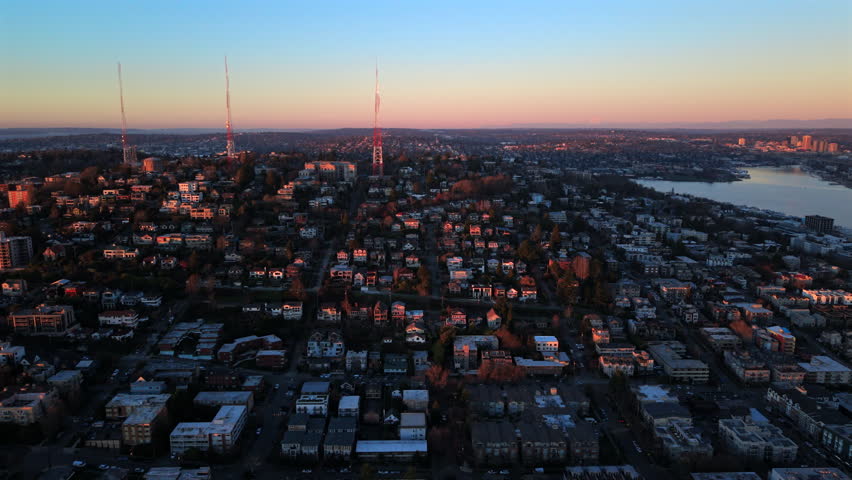 Aerial panorama of Seattle Washington residential area cityscape, evening light outlining dense neighborhoods, modern skyline and expansive waterways.