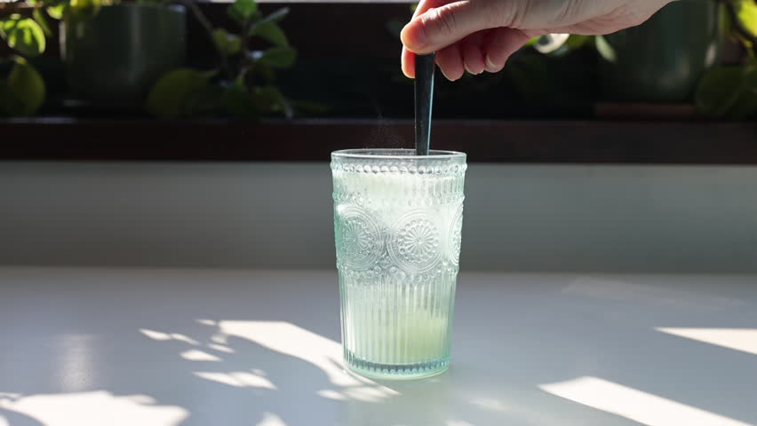 pouring and mixing collagen powder in a glass of water