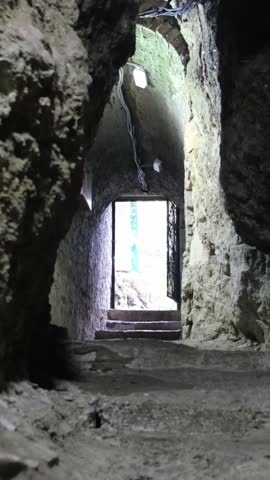 Person walking up ancient stone stairs toward daylight